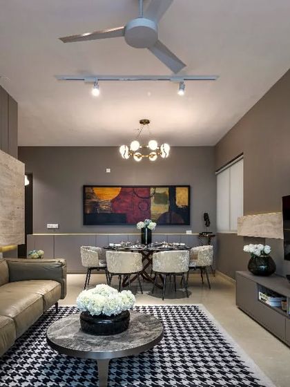 This wider view of the same apartment living room shows how the different zones for living and dining are defined within an open-plan layout. The consistent color scheme and strategic lighting create a cohesive and elegant atmosphere.