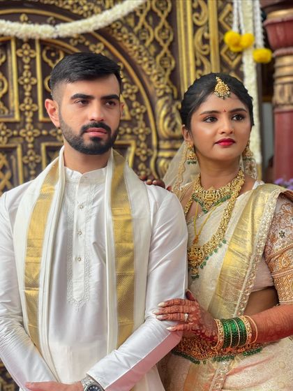A formal portrait of the bride and groom. Her traditional attire is complemented by classic makeup with a bold red lip and defined eyes.