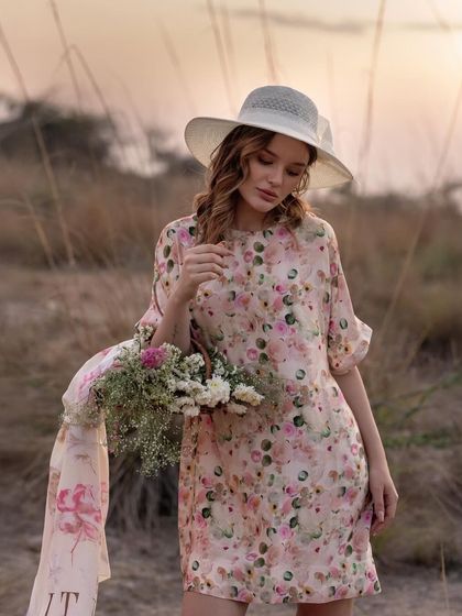 This image uses props like a flower basket to build a story around the floral dress. The downward gaze creates a soft, romantic mood perfect for a spring or summer collection.