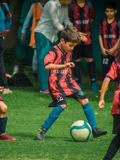 A young player dribbles through traffic, surrounded by other players.
