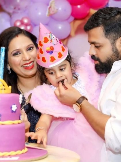 A sweet moment as a father helps his daughter, the birthday girl, take her first bite of cake.