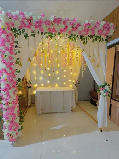 A beautiful and complete mandap setup for your home. The pink and white floral arch is complemented by soft drapes and delicate hanging details.