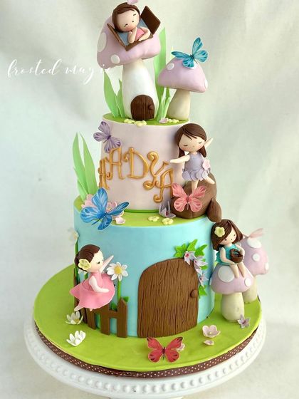 I designed this two-tiered cake as a whimsical fairy and mushroom village. It’s filled with tiny, handmade fairies, edible butterflies, and cute mushroom houses, creating an enchanting scene for a first birthday.