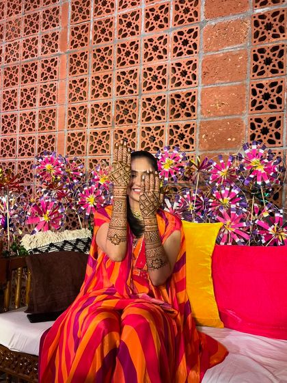A playful peek-a-boo pose from Rupa, her smile shining through her hennaed hands.
