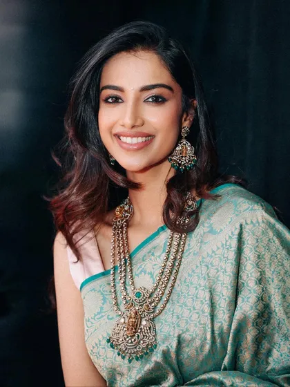 A beautiful portrait in a light teal silk saree, paired with a stunning multi-layered traditional necklace. This styling balances classic elegance with a soft, modern feel.