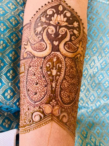 This bridal arm band design features two peacocks forming a heart shape, with a lotus blooming above them. It's a very romantic and popular motif for brides.