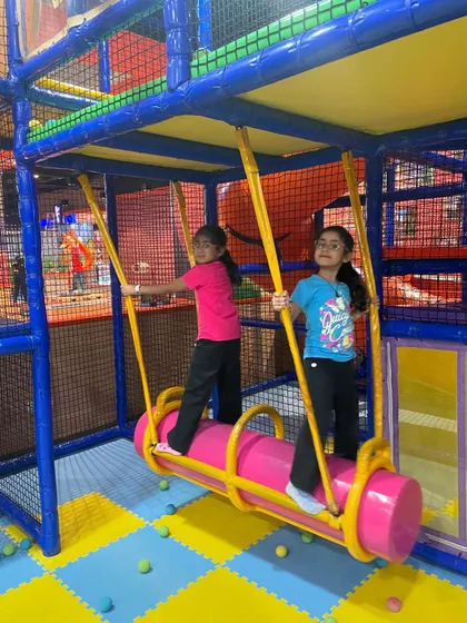 Two friends enjoying the swinging log ride, a classic feature that encourages cooperative play.