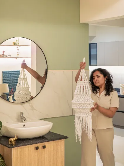 The final touches are what bring a space to life. Here, I'm placing a handmade macrame lantern in a transitional nook between the kitchen and common rooms. We turned a neglected corner with a sink into a subtle, textured focal point using a pastel green wall, a simple wood vanity, and thoughtful lighting.