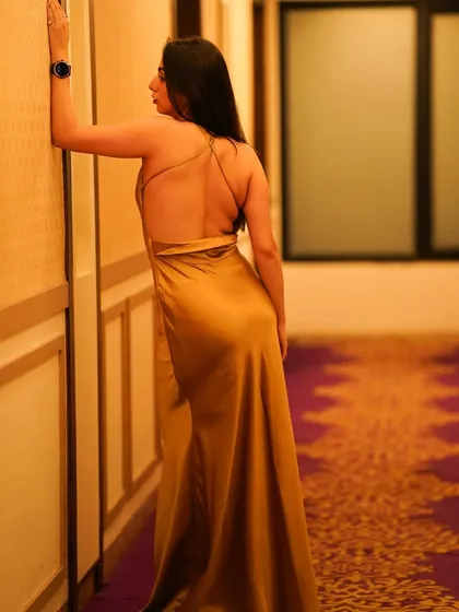 A full-length back view of the golden gown, highlighting the open back and the way the fabric drapes.