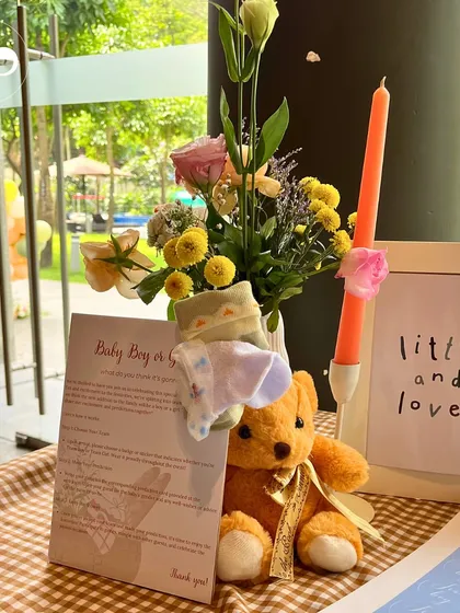 A charming corner of our barnyard themed shower. A small teddy bear sits next to a "Baby Boy or Girl" guessing game card and a sweet sign that reads "little and loved," creating a heartwarming vignette.