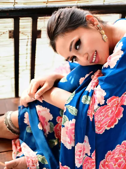 A happy and relaxed portrait of actress Mimi Chakraborty. Her genuine smile and the casual pose on a wooden bench create a warm and approachable image.