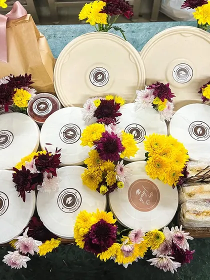 A beautifully assembled gift tray, featuring a variety of our meal bowls and sandwiches, decorated with fresh flowers. It's the perfect gift for a loved one.