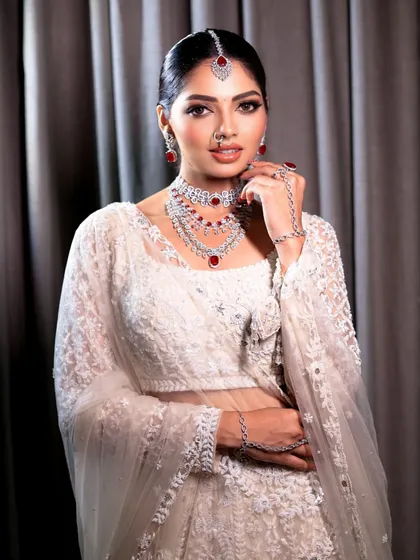 A confident pose from the bride, showcasing her full look. The sleek hair bun and radiant makeup create a very polished and regal appearance.