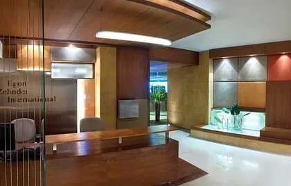 The reception area at the Egon Zehnder office, featuring a custom wooden desk and a feature wall of leather and metal panels.