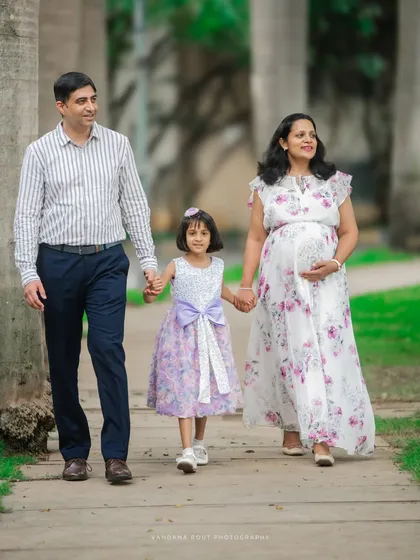A happy family of three, soon to be four, walking hand-in-hand through a park. I love including older siblings to capture the family's growing love story.