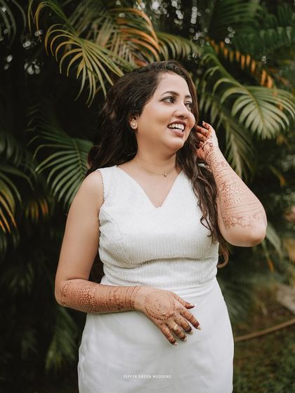 A candid portrait of the bride, her joyful laugh captured perfectly. Her henna-adorned arms add a beautiful traditional touch.