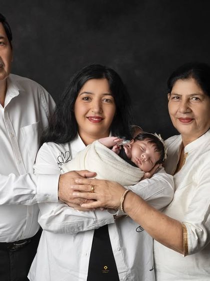 A tender moment with the new mother and grandparents holding the baby. The classic white outfits create a clean, timeless look that focuses all attention on their loving connection.