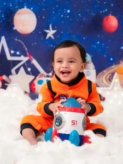 A happy little astronaut with his toy rocket. Themed props help engage children and bring out their most playful and genuine smiles.