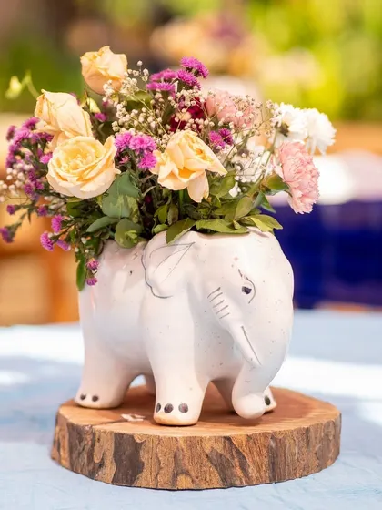 Centerpieces are a chance to be creative and sustainable. This adorable elephant-shaped ceramic vase, filled with local flowers and placed on a reclaimed wood slice, was a charming detail for the Mexican themed event.
