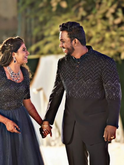 For a glamorous evening event, you can't go wrong with a coordinated black and blue theme. The groom's black Jodhpuri suit with intricate beadwork pairs beautifully with this sparkling navy blue gown.