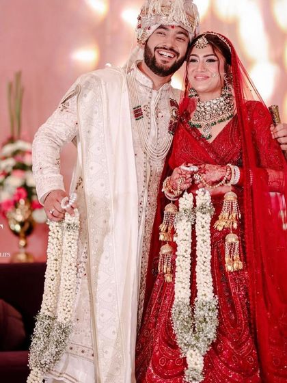 A happy moment captured between the bride and groom. She is wearing our heavy polki and green stone set with her red lehenga.
