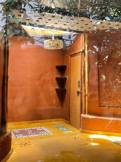 The entrance to the cottage, with yellow oxide flooring inlaid with waste Athangudi tiles, and walls finished with a natural mud wash.