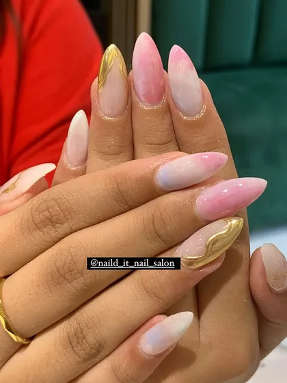 A beautiful blend of pink and white ombre with delicate gold chrome accents. This design on long almond nails offers a soft yet glamorous look.