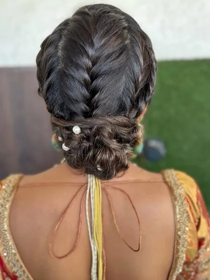 A classic low bun with a twist. I created a French braid leading into the bun and added a few pearl pins for a touch of elegance. This is a timeless choice for any formal occasion.