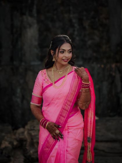 The bride poses gracefully, her hand gently touching her hair. This portrait showcases her complete engagement look, from the elegant saree to the traditional jewelry.