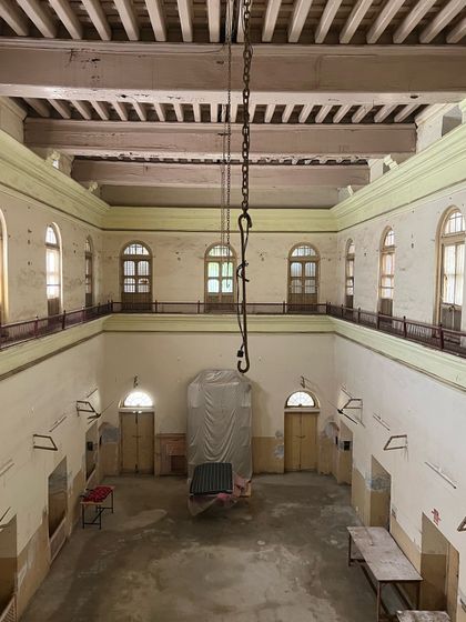 The grand central hall of the haveli, a double-height space with a wooden beam ceiling and galleries, awaiting its transformation.