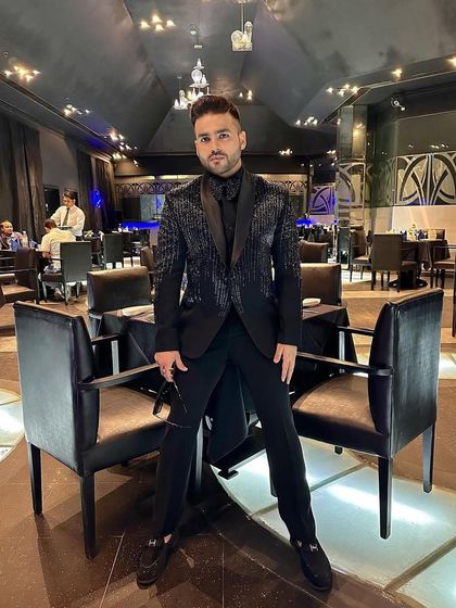 A client in an all-black look, featuring our tuxedo with vertical sequin stripes. This is a sleek, modern, and edgy choice for an evening event.