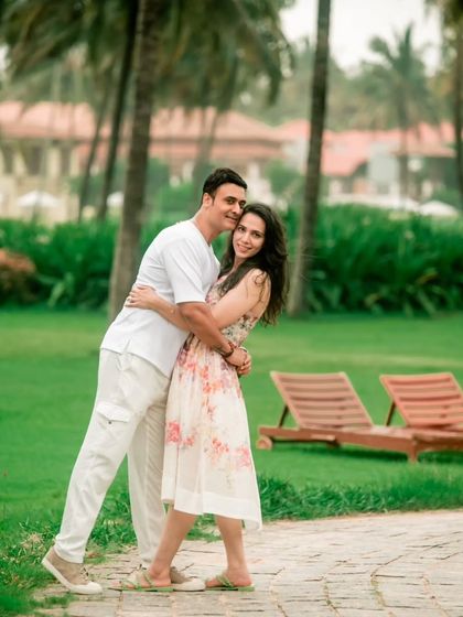 A classic portrait of the couple looking towards the camera, framed by the beautiful greenery and palm trees of a resort.
