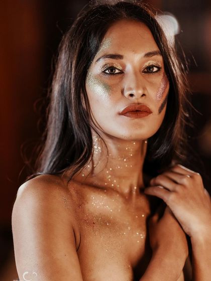 A beautiful and serene close-up. The glitter acts as a second skin, creating a unique and artistic beauty portrait.