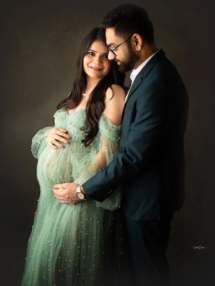 A classic and intimate couple's portrait. The dad-to-be gently holds the baby bump, both sharing a quiet, happy moment.