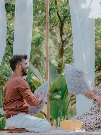A playful pillow fight during a picnic-style pre-wedding shoot. This fun and energetic activity brings out genuine laughter and creates dynamic, memorable photos that show the couple's lighthearted connection.