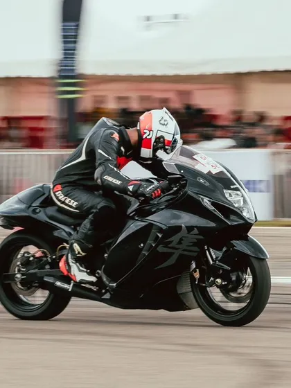 A rider on a black Suzuki Hayabusa, a legendary name in the world of speed, blasts down the drag strip.