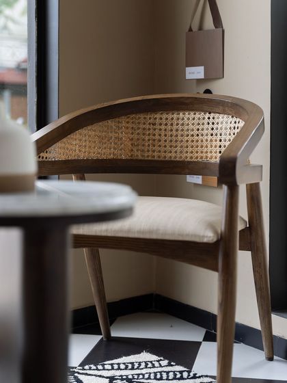 This classic wooden chair with a curved, caned back is another piece from our House of Goya collection. It represents our focus on creating furniture that blends traditional techniques with contemporary silhouettes.