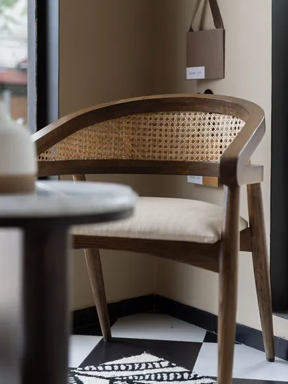 A classic armchair with a curved back and cane webbing, crafted from solid wood. This piece exemplifies our modern-vintage aesthetic, blending timeless materials with a contemporary form.