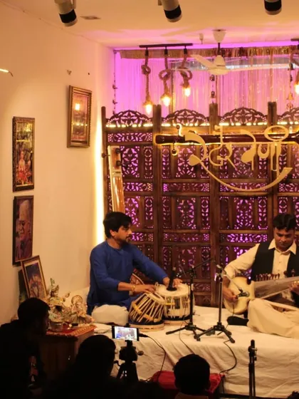 A wide view of our monthly Swarveni Baithak, featuring Sh. Imran Khan on the Sarod. The traditional decor and attentive audience create an authentic setting for enjoying Indian classical music.
