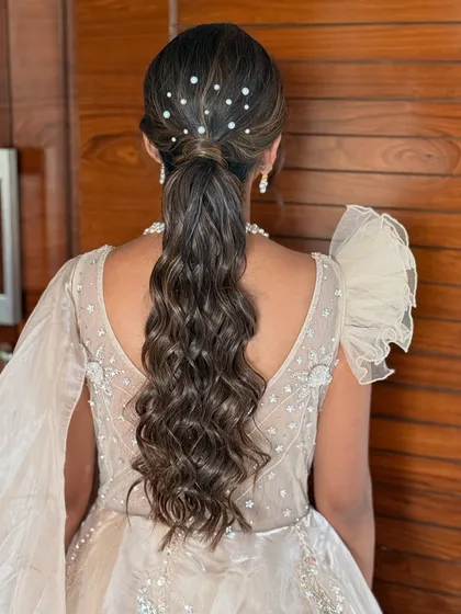 A beautiful ponytail with soft waves and delicate pearl accessories. This hairstyle is elegant, modern, and perfect for a reception or cocktail party.