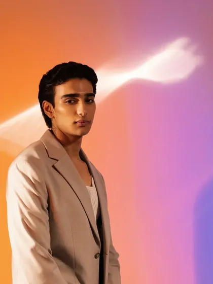 A different look from the same shoot, this time with slicked-back hair and a focus on glowing, healthy-looking skin against a colorful backdrop.