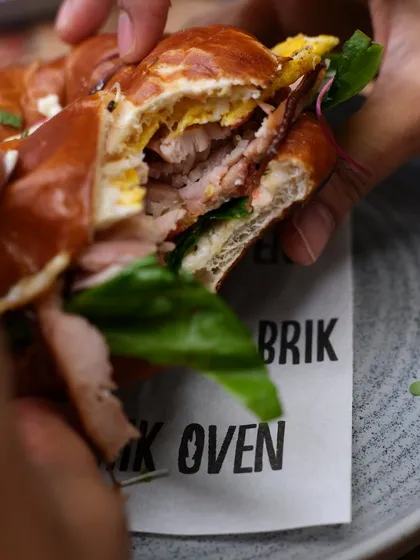 The cross-section of our pretzel bagel sandwich, revealing the layers of juicy ham, egg, and fresh lettuce inside the chewy bread.