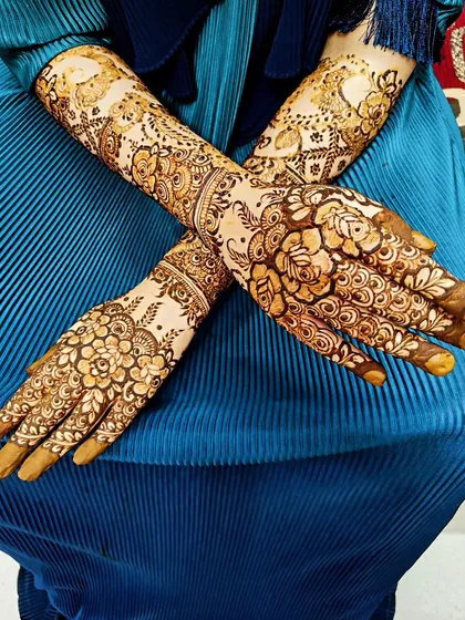 A crossed-hands pose showing the beautiful symmetry and flow of this engagement henna design.