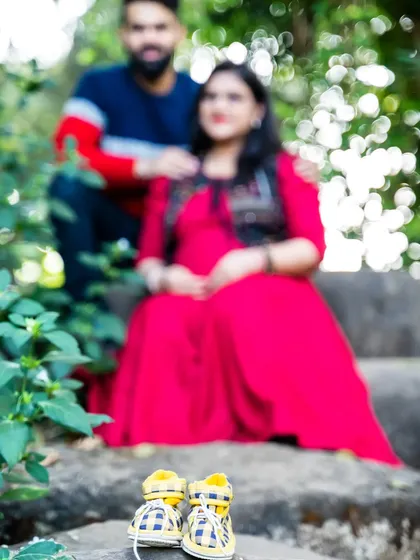 A creative shot with a focus on the tiny baby shoes in the foreground, with the happy couple blurred softly in the background.