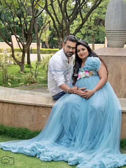 A beautiful portrait of the couple seated on a stone bench in a lush garden. The flowing blue gown adds a touch of fairytale magic to the natural setting.