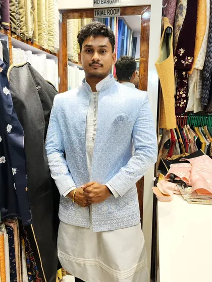 A client models a sky blue open Jodhpuri jacket with delicate white embroidery. Paired with a white kurta and pant combo, this outfit is a perfect blend of classic and contemporary style.