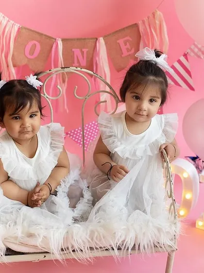 Two little princesses in pink for their twin first birthday photoshoot! The studio was decorated with balloons and a "ONE" sign to make their celebration extra special.