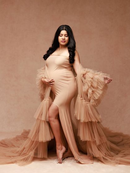 The tiered ruffles on the sleeves and train of this nude gown add a wonderful sense of drama and texture to this elegant portrait.
