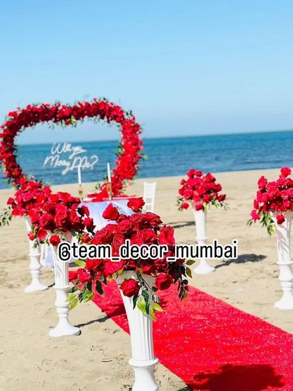 Another perspective of the beach proposal decor, highlighting the floral arrangements on pillars that line the aisle.