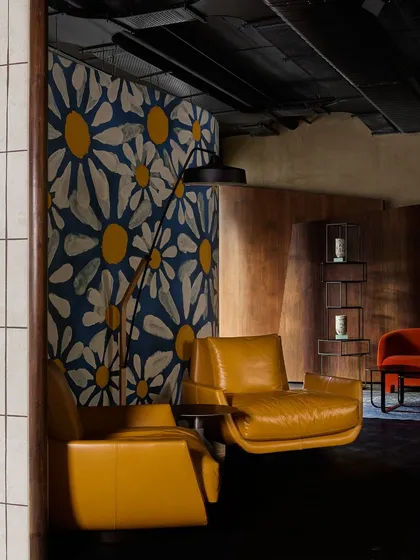 A bold, artistic vignette featuring mustard yellow leather armchairs against a large, hand-painted floral screen. This shows how art and furniture can be integrated to create a powerful statement.